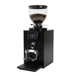 A black electric coffee grinder with a clear hopper on top, a digital control screen, a metal chute, and a drip tray, shown against a plain white background.